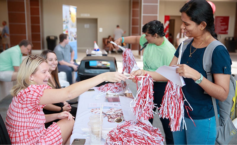 a recruiter hands a woman a crimson and white shaker.