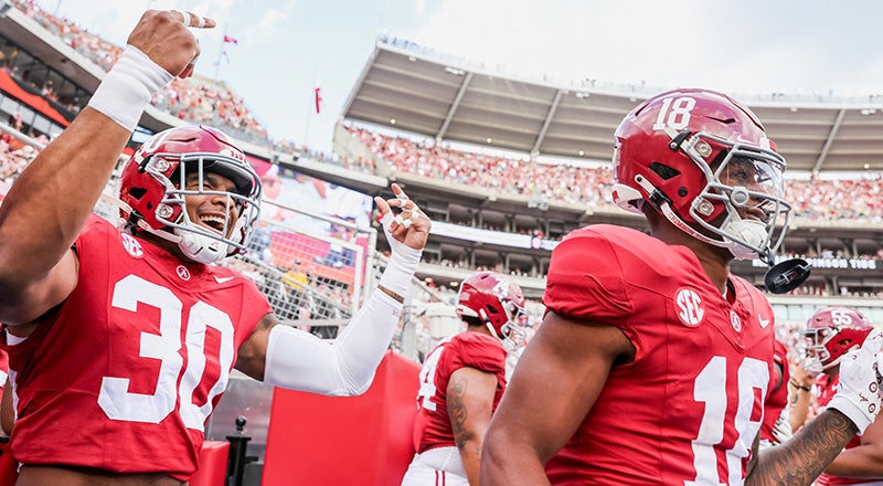 up close photo of the alabama football team running onto the field at bryant-denny stadium