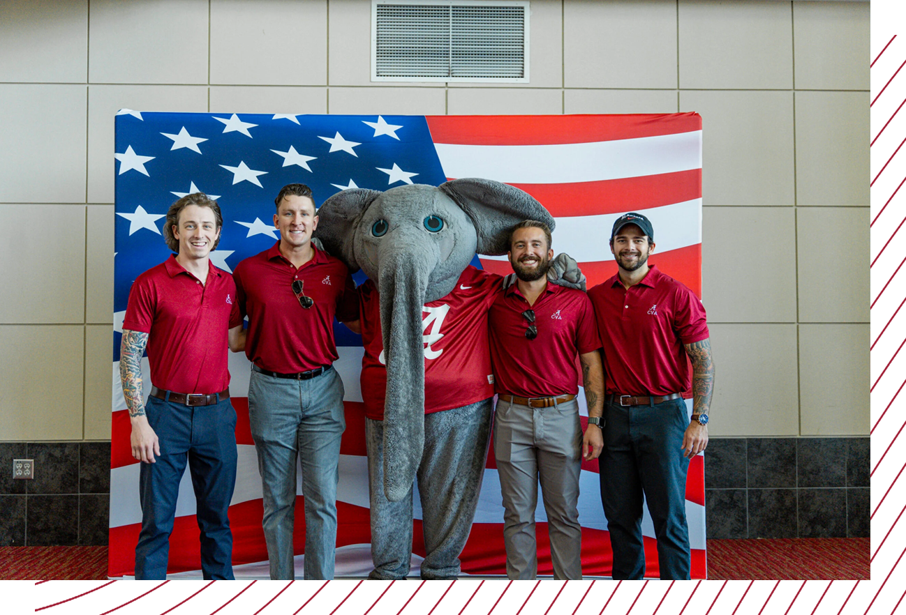 Student veterans stand with Big Al in front of an American flag background.