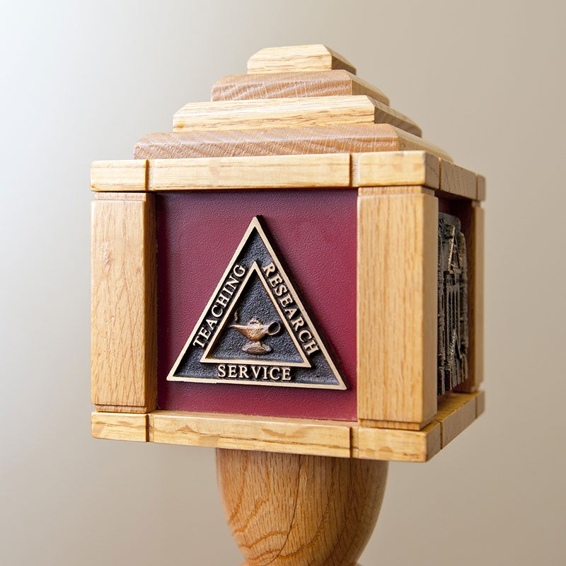 Ceremonial mace side showcasing emblem for teaching, research and service